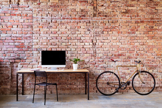Workspace and bicycle at brick wall in office