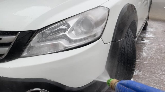 Crystal clear water flows across the freshly washed vehicle, leaving a spotless painted surface with brilliant reflections, perfect for automotive detailing and cleaning concepts.