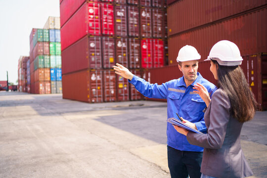 Logistics worker pointing towards container yard for businesswoman