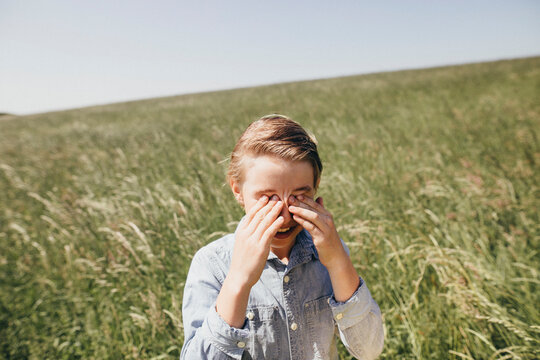 Boy on a field rubbing his eyes