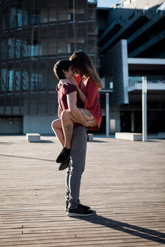 Young man lifting up girlfriend on city square