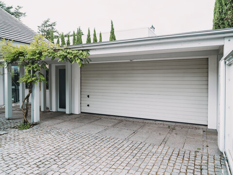 Modern villa exterior with cobblestone courtyard and garage door