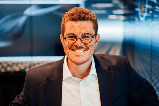 Smiling businessman with freckles looks at camera in a TV studio