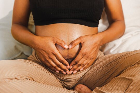 Pregnant woman making heart shape with hands on belly