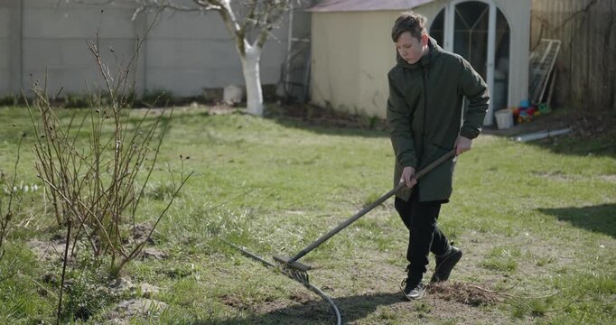 Kid Rakes Grass on Lawn. Caucasian Boy Help Working Around Backyard. 4K 10-bit