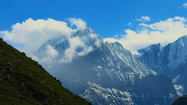 4K Landscape shot of snowy Himalayan mountain peak surrounded by clouds during the summer season as seen during the Ghepan Ghat Lake trek near Sissu village in Lahaul Valley, Himachal Pradesh, India. 