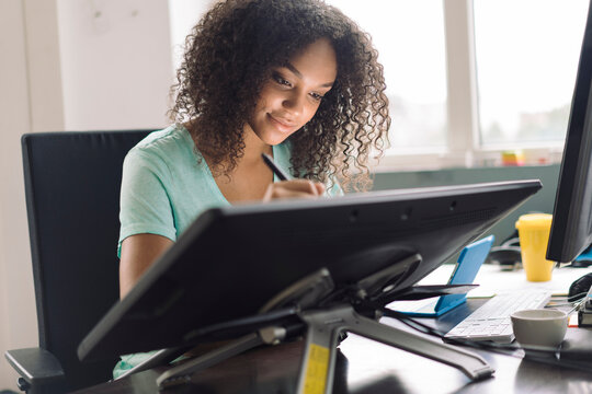 Young female designer drawing on digital tablet