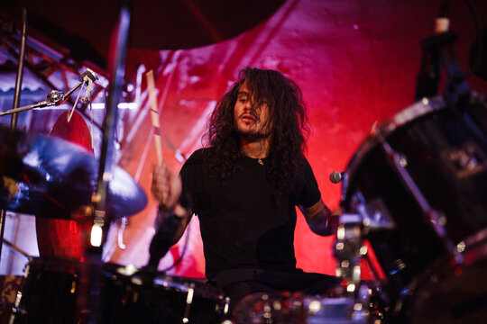 Concert of drummer playing drum kit while performing on stage in live event