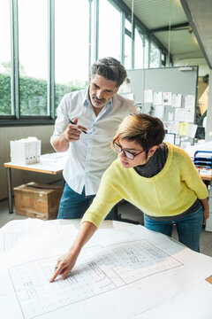 Male and female architects discussing ground plan in office