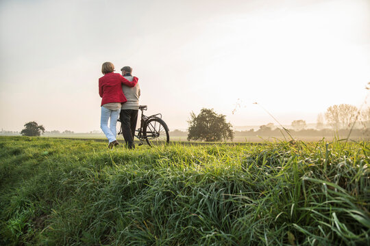 Senior man and daughter in rural landscape with bicycle