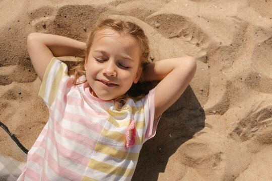 A smiling girl enjoys her summer vacation on the beach sand