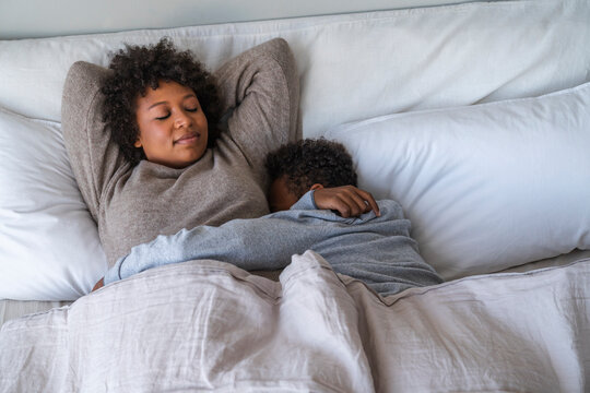 Mother and son sleeping on bed at home