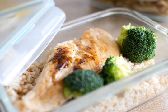 Grilled chicken breast with brown rice and broccoli in glass meal prep container. Close up