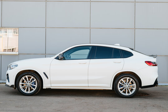A white BMW X4 is parked beside a modern building in an urban area during daylight. The vehicle is facing sideways, showing its sleek design and sporty outline Smolensk, Russia 07.17.2026