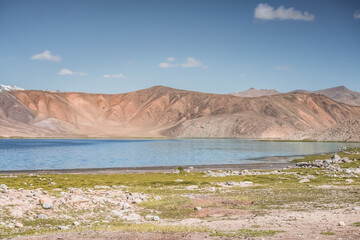 Clear-water rivers and lakes in a mountain valley, pastures and green grassy fields set against mountain ranges and snow-capped, glacier-clad peaks—a scenic landscape background © Denis