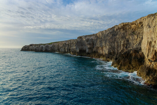 Dramatic coastal cliffs meet the wavy ocean under an overcast sky long rocks panorama overcast water surface south travel landscape