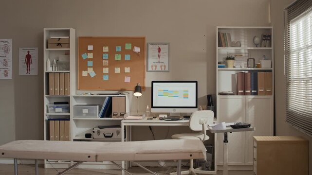 Empty medical clinic office featuring examination table, computer desk, and anatomical posters. Serving as establishing shot for healthcare marketing and clinic promotional videos