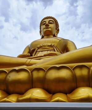 Low angle view of the giant golden Buddha statue, Phra Buddha Dhammakaya Thep Mongkol, at Wat Paknam Phasi Charoen temple in Bangkok, Thailand.