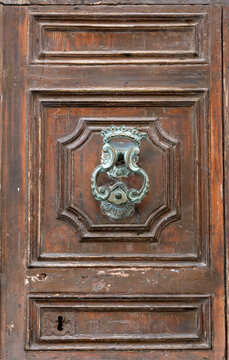 Ornate metal door knob knocker on old wooden door