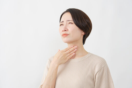 白背景で喉の痛みに苦しむ40代女性