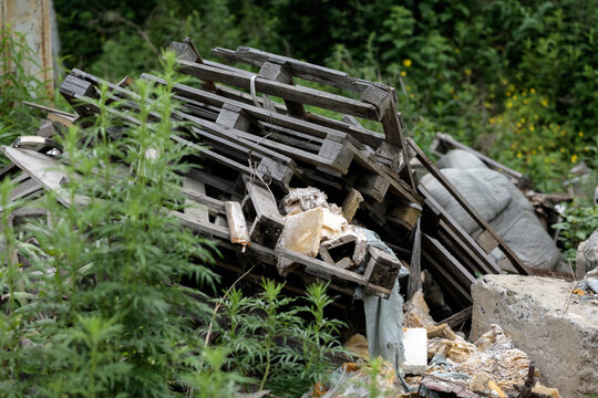 Pile of old wooden pallets and construction debris outdoors.