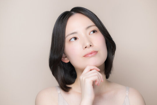 Japanese women struggling with skincare and beauty concerns; a natural close-up portrait evoking the image of beautiful skin; looking up
