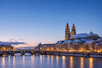 Obraz premium Zurich city skyline at winter twilight with snow-covered Grossmunster church, historic buildings, and bridge lights reflecting in the Limmat river.