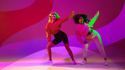 Diverse young dance duo performing against bold magenta background. Concept of inclusive dance...