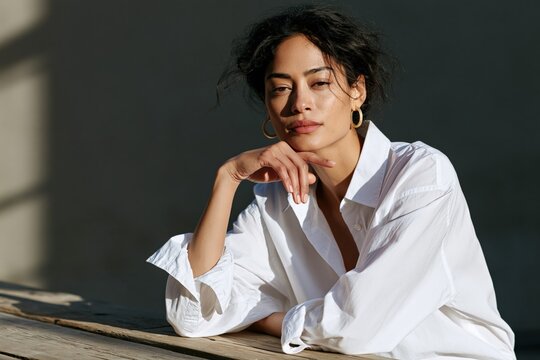 Natural light female portrait in a white shirt seated at a rustic wooden table for lifestyle banner design and editorial background