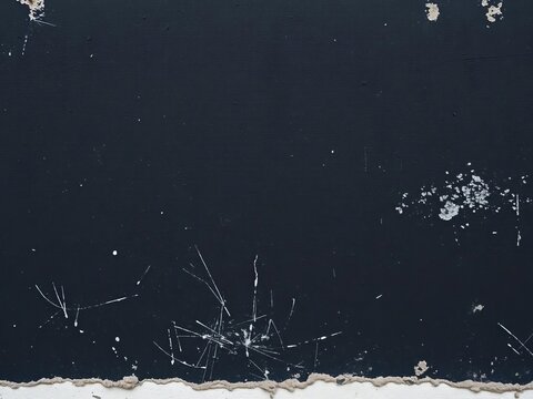 Weathered black stucco wall with white scratches and scuffs, aged, rustic