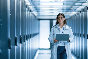 Fototapeta premium Female Scientist Working on Laptop in Modern Data Center Server Room