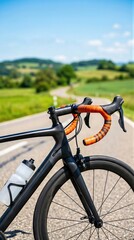 Fototapeta premium Carbon road bicycle handlebars with orange tape on a paved country road. Professional racer bike for training or sports competition outdoors. Concept of healthy lifestyle and cycling hobby.