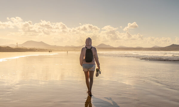 Solo traveler exploring a vast scenic beach during golden hour