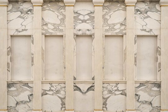 Symmetrical interior wall facade with five recessed niches framed by fluted columns and white marble panels featuring grey vein textures