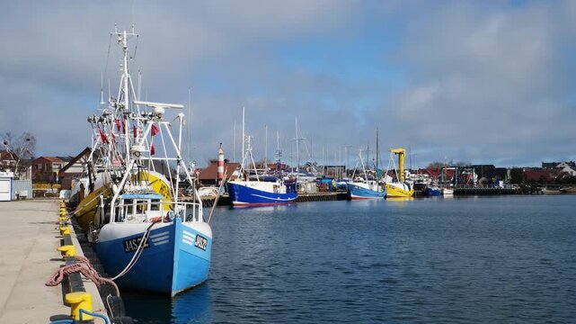 Colourful traditional fishing boats moored at the scenic port of Jastarnia on the Hel Peninsula, Poland, gently swaying in the calm Baltic waters on a bright, sunny day.