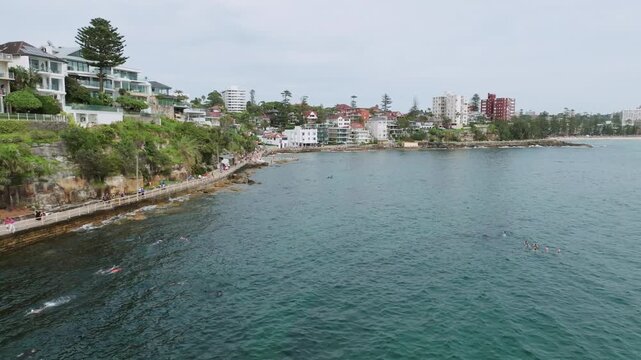 Cinematic Drone Flight Along Shelly Beach Waterfront Revealing Crystal Clear Ocean, Coastal Walk, Luxury Homes and Sydney Harbour Shoreline in Manly Australia