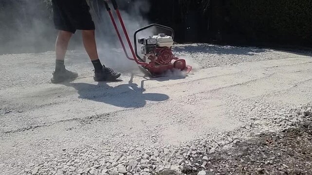 Landscape gardener industrial stone foundation compactor machine slow motion stamping dusty surface