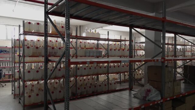 Rows of cardboard boxes neatly stacked on tall industrial pallet racks inside a dimly lit warehouse storage area
