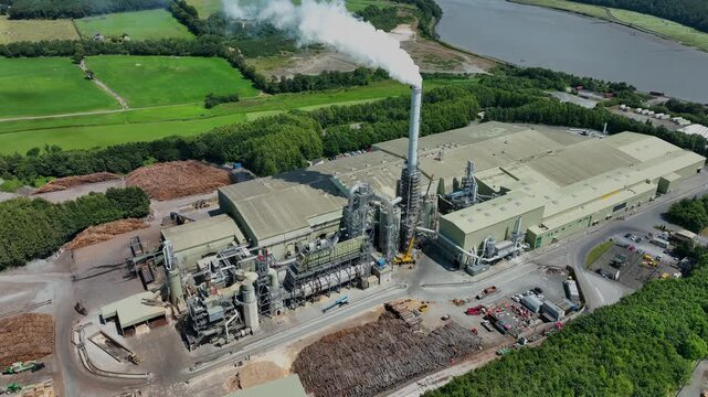 Aerial view of wood processing plant next to Suir River Waterford Ireland stock of logs and steam emitting from chimney on a summer day in Ireland