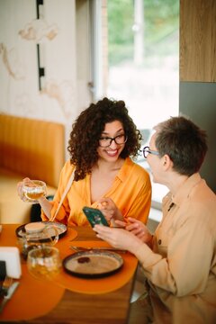 Generational women sharing laugh using smartphone at cafe