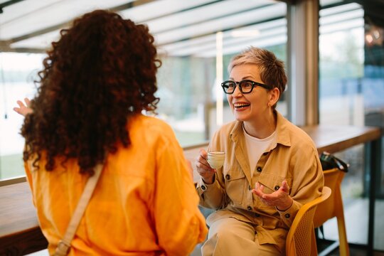 Two women enjoying coffee talking cheerfully in cafe