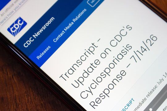 Mexico City, MEXICO - Jul 21 2026 : Close-up of a smartphone on a wooden surface showing the CDC Newsroom webpage with a transcript titled Update on CDC's Cyclosporiasis Response.