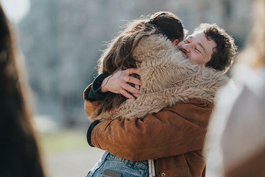 Two friends embrace tightly while smiling and sharing a happy moment. A warm outdoor reunion captured as they hug in winter coats.