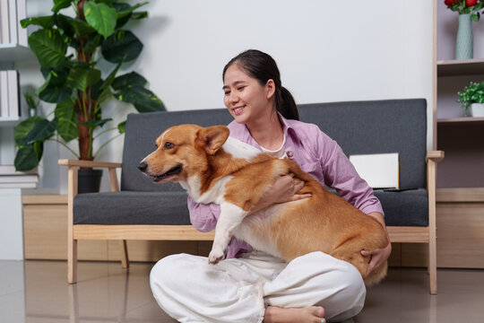 Asian woman hugging her corgi dog in living room for pet companionship