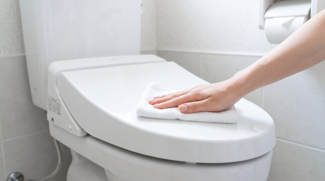 トイレの便座ふたをクロスで拭き掃除する様子・清潔で衛生的なトイレお手入れ