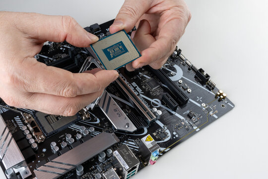 Maykop, Russia - February 18, 2025: men's hands hold the new Intel processor above the Asus motherboard close up