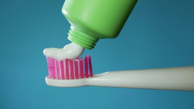 Close-up of toothpaste being squeezed onto a pink toothbrush head