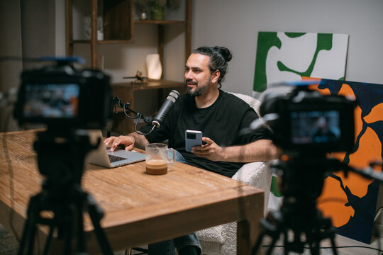 Video podcast recording studio. A young man is sitting at a table in front of a microphone in the frame. The host of the program is filming an episode of the Internet show.