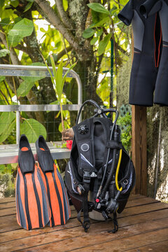 Detail shot of scuba diving gear ready for the water with set of fins, BCD, octopus regulator, dive tank and a hanging wet suit
