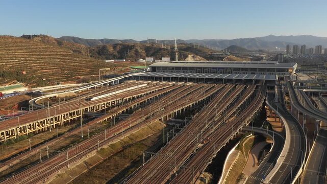 Drone shot of high-speed bullet train leaving massive modern Kunming South railway station in China
